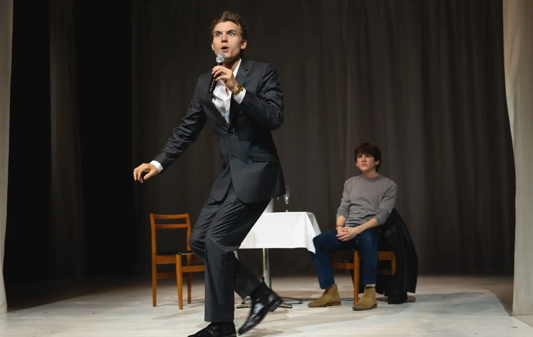 Ferdinand McKay performing with microphone in suit on stage